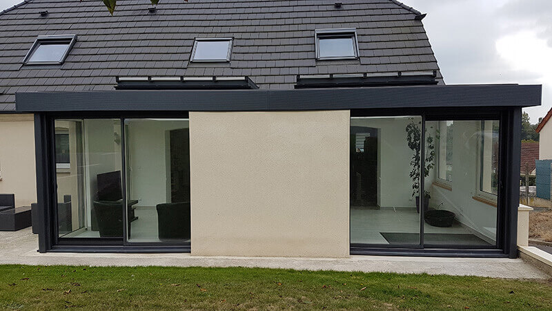Extension d'habitation de type toiture plate de couleur gris foncé avec 2 dômes mono-pente