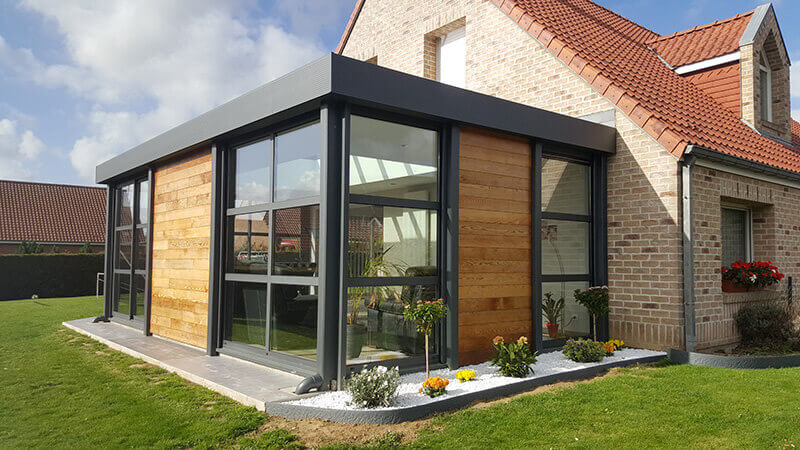 Extension d'habitation de type toiture plate de couleur gris foncé avec dôme mono-pente