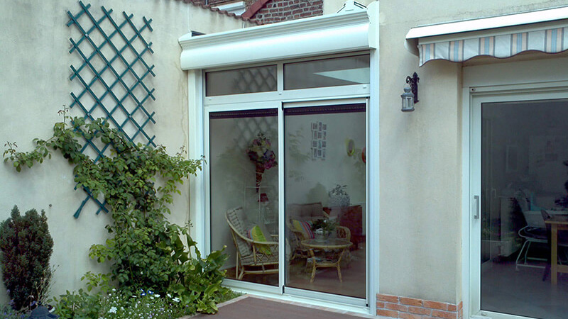 Véranda de type toiture plate de couleur blanc avec dôme double pente, coffre de volet roulant et chéneau mouluré après rénovation