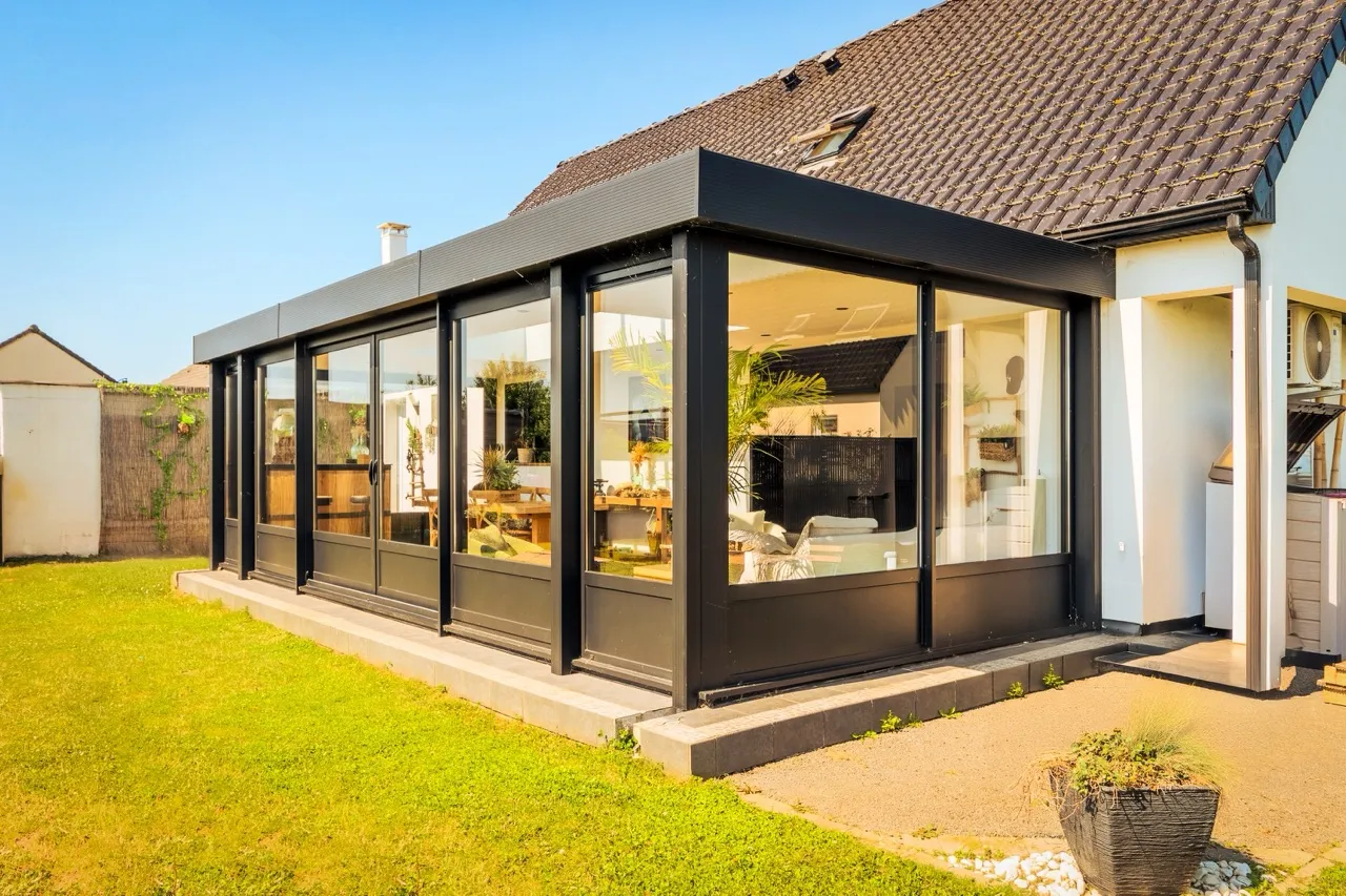 Extension Véranda dans un jardin avec une pelouse verte