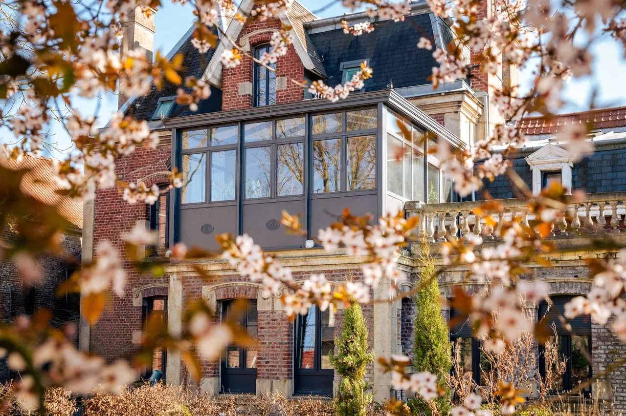 Véranda en extension d'une ancienne bâtisse entourée de branche