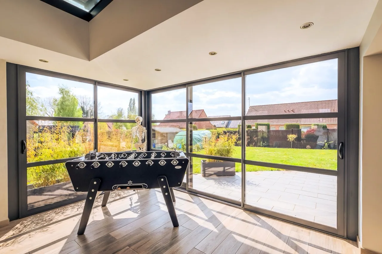 Intérieur d'une Véranda avec de grandes baies vitrée et un babyfoot au centre