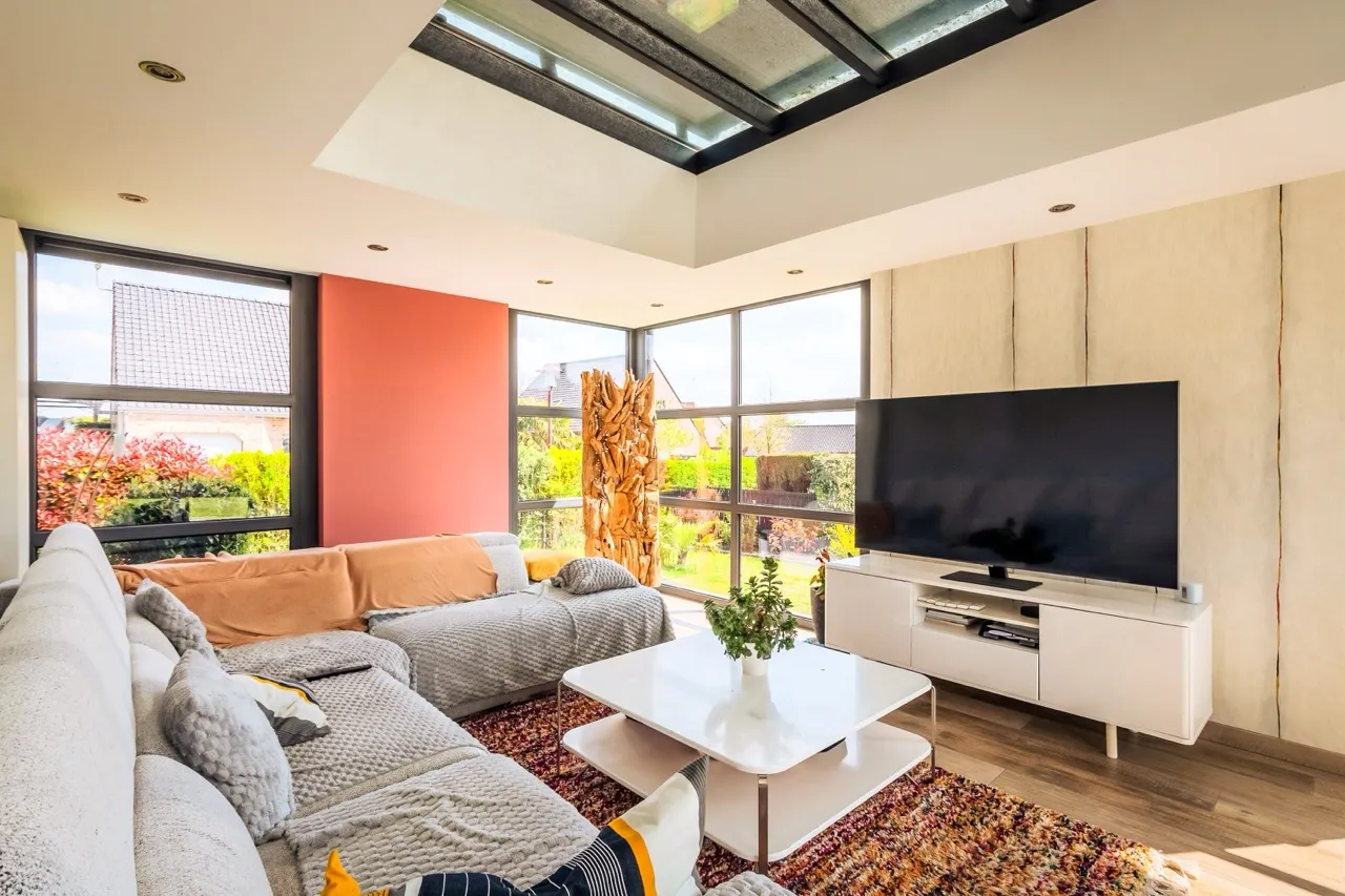 Intérieur Véranda dédié à un espace de vie avec un canapé, une télévision et de grandes baies vitrée