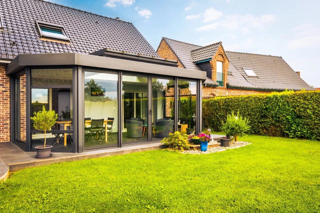 Extension Véranda dans un jardin avec une pelouse verte